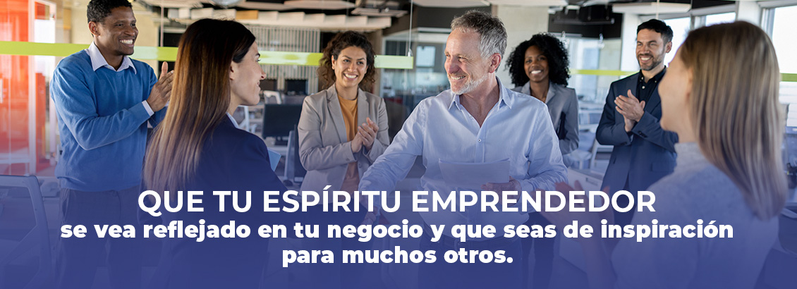 Hombre sonriente recibiendo reconocimiento y aplausos del equipo de trabajo.